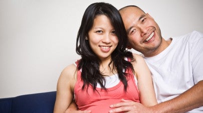 Pregnant woman with man hugging her and her stomach | WWMG