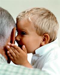 Child whispering into Grandpa's ear