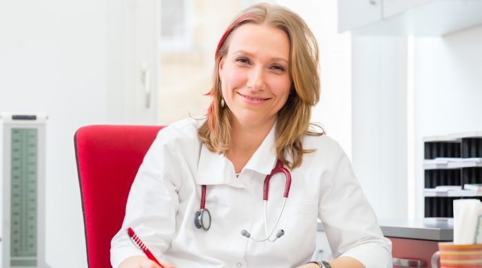 Young gynaecologist writing medical prescription in surgery at desk