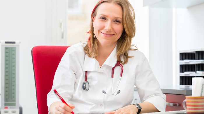 Young gynaecologist writing medical prescription in surgery at desk