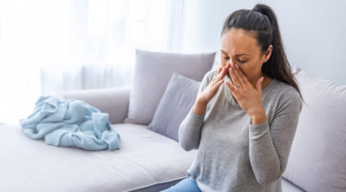Sinus ache causing very painful headache. Unhealthy Asian woman in pain. Sharp strong sore. Sinus pain, sinus pressure, sinusitis. Sad woman holding her nose and head because sinus pain