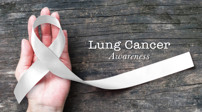 Lung cancer awareness month with white/ light pearl color ribbon on woman's hand support on aged wood