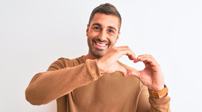 Young handsome elegant man wearing winter sweater over isolated background smiling in love showing heart symbol and shape with hands. Romantic concept.