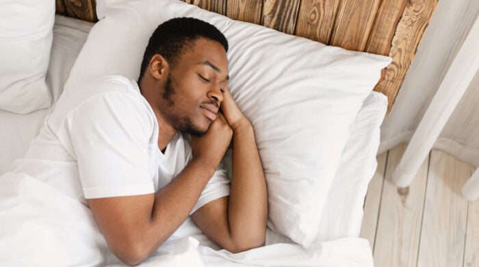 African American Man Sleeping Peacefully Resting With Eyes Closed Lying In Comfortable Bed In Bedroom At Home. Recreation, Healthy Male Sleep, Bedtime Napping Concept. Empty Space For Text