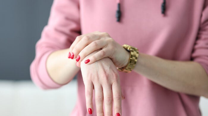 Woman with red manicure holding her wrist joint closeup. Diagnosis and treatment of arthritis concept