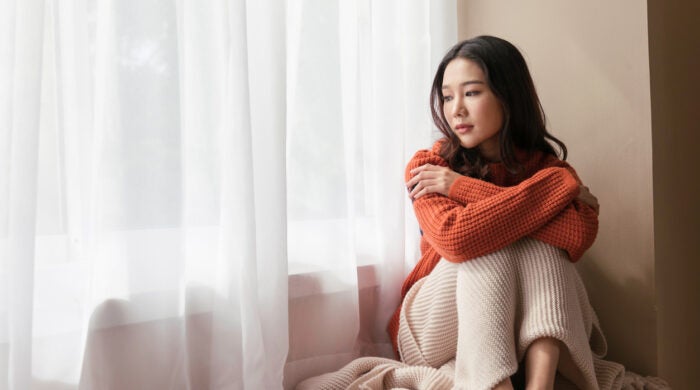 A beautiful Asian woman. young women the pensive face looking away thinking of problems sit alone at home, Sad eyes, Winter sadness