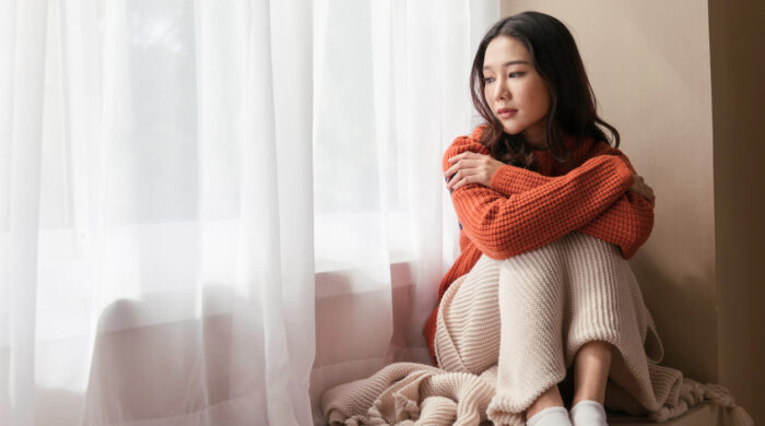 A beautiful Asian woman. young women the pensive face looking away thinking of problems sit alone at home, Sad eyes, Winter sadness
