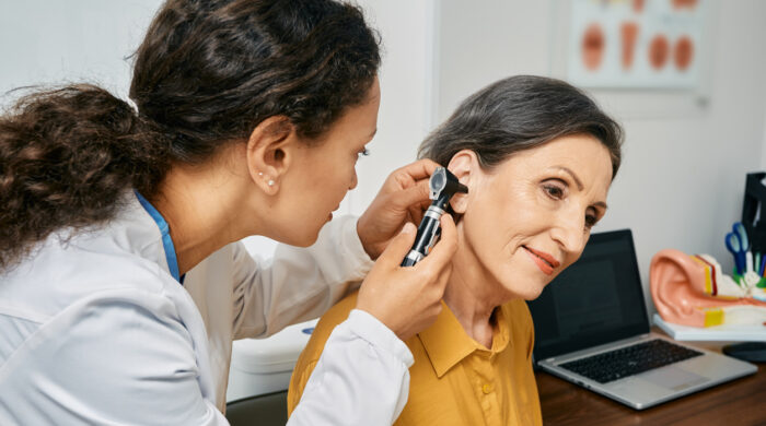 Hearing exam for elderly citizen people. Otolaryngologist doctor checking mature woman's ear using otoscope or auriscope at medical clinic