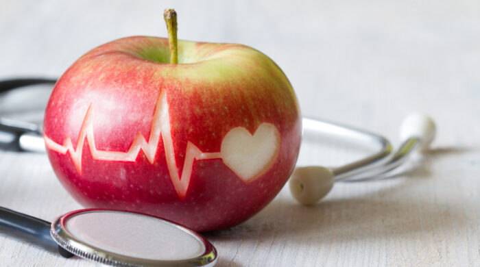 Heartbeat line on red apple and stethoscope, healthy heart diet concept background