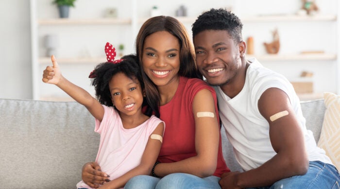 Vaccination Concept. Portrait Of Black Vaccinated Family Of Three With Adhesive Bandage On Arms, Happy African American Mother, Father And Little Daughter Posing At Home After Covid-19 Vaccine Shot