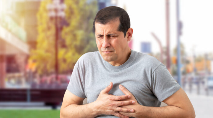 Shot of a man holding his chest in discomfort due to pain in the street during the day.Heart attack concept.