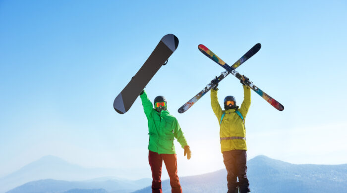 Skier and snowboarder stands mountain top with ski and snowboard in hands. Skiing and snowboarding concept. Sheregesh ski resort