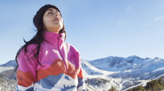 Relaxed woman breathing fresh air in a snowy winter mountain . Winter time